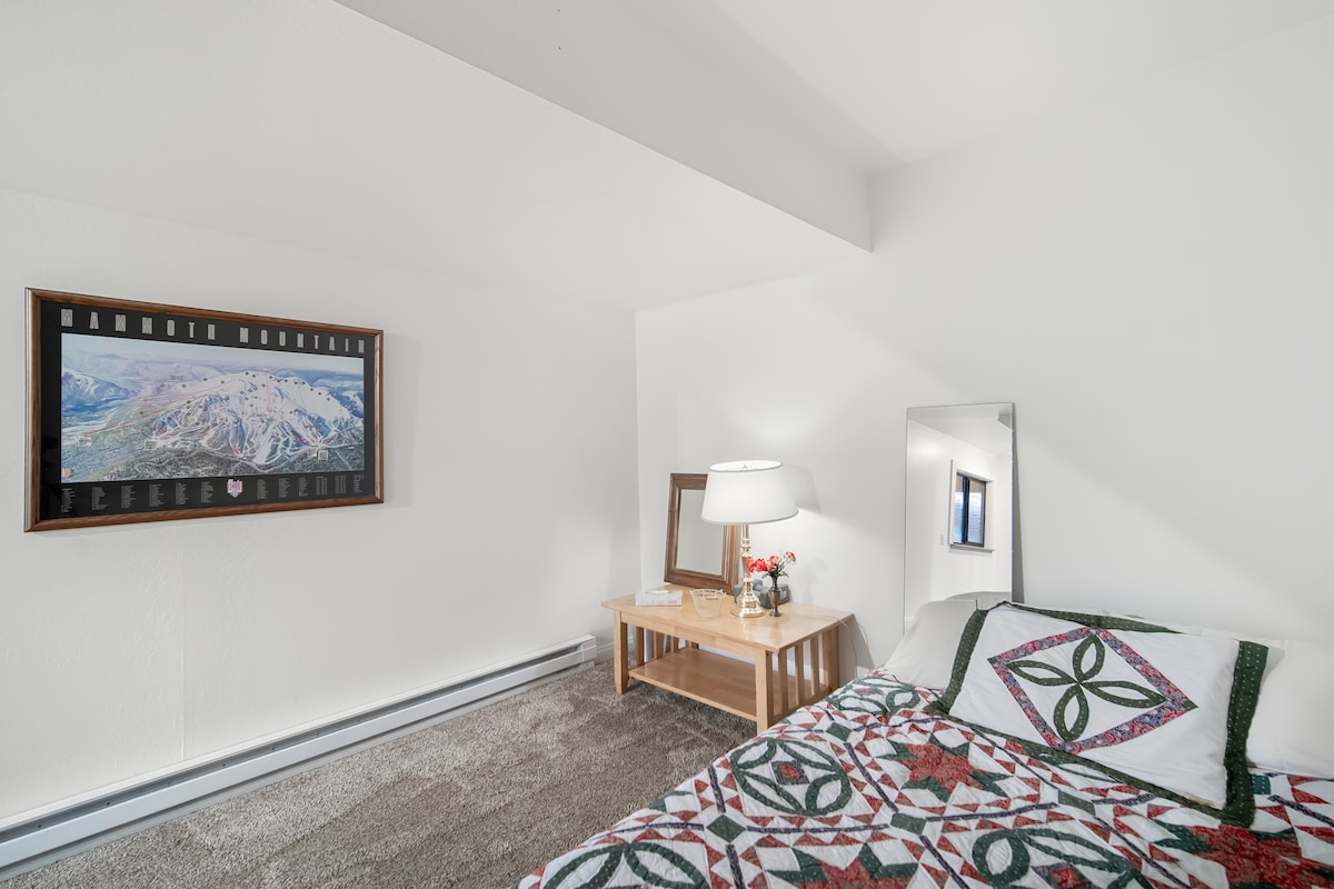 Dormitorio espacioso con alfombra para la calidez y las paredes blancas para mantener las cosas brillantes. 