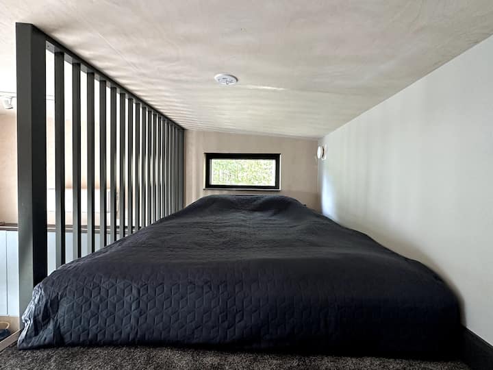 Roshani ya kulala. Ngazi za roshani zilizo na msimamizi upande mmoja zinaelekea kwenye roshani. Picha inapanua moja ya vitanda viwili.