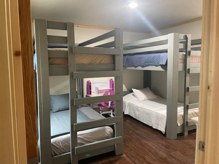 4 Twin beds in the form of 2 upper and 2 lower bunk beds. There is a small children’s desk with coloring books, crayons and dry erase markers.