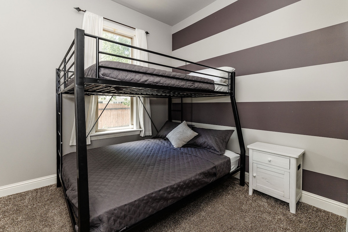 ผ่อนคลายในห้องไลแลคด้วยเตียงสองชั้นที่มีฟูกขนาดควีนไซส์อยู่ด้านล่างและฟูกนอนเต็มรูปแบบด้านบน มีโต๊ะข้างเตียงตัวเดียวที่มีพาวเวอร์แบงค์อยู่ทางด้านขวาทำให้การชาร์จอุปกรณ์เป็นเรื่องง่าย