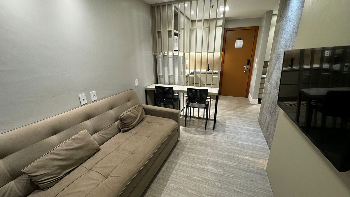 sofá cama, TV, mesa y dos sillas.