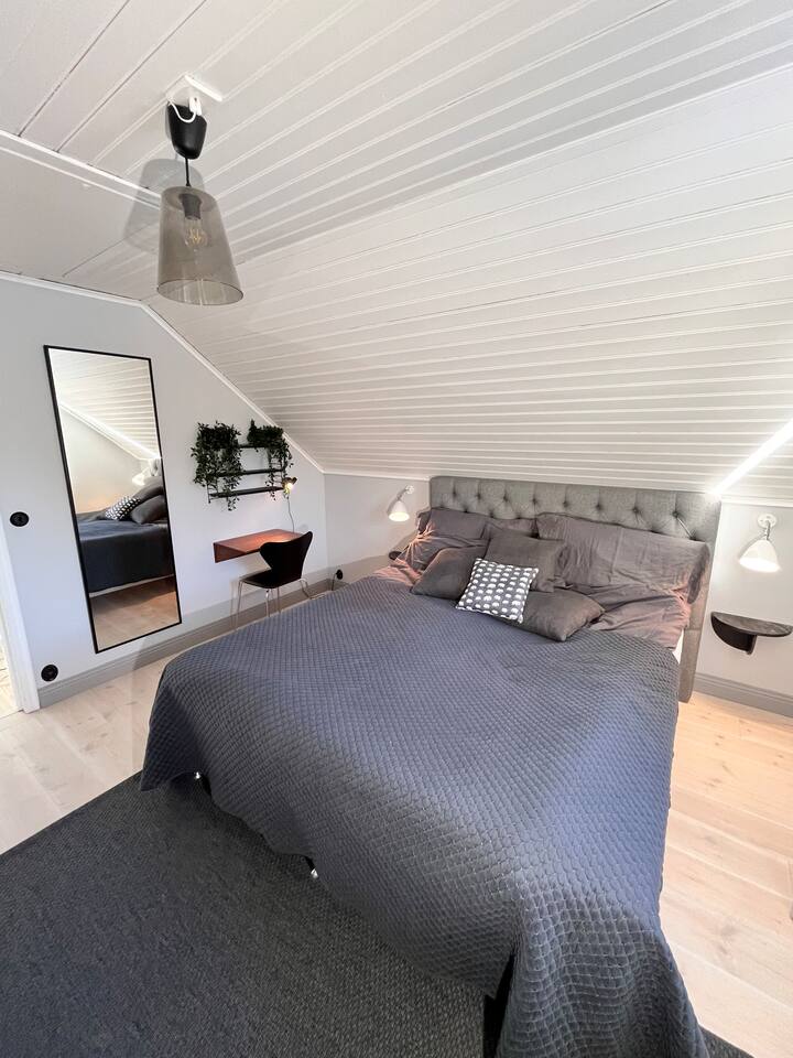 Საძინებელი ზემოთ დიდი ზომის საწოლით, ტელევიზორითა და სამუშაო მაგიდით.