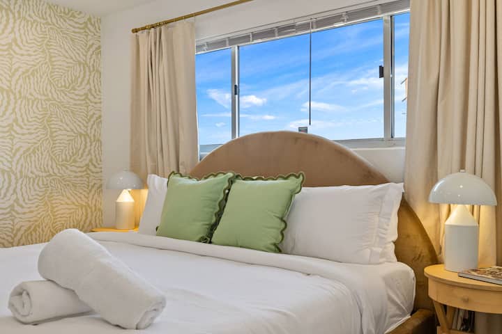 Útulná spálňa so zelenými prvkami a príjemným osvetlením, stvorená pre pokojné noci a pomalé rána.