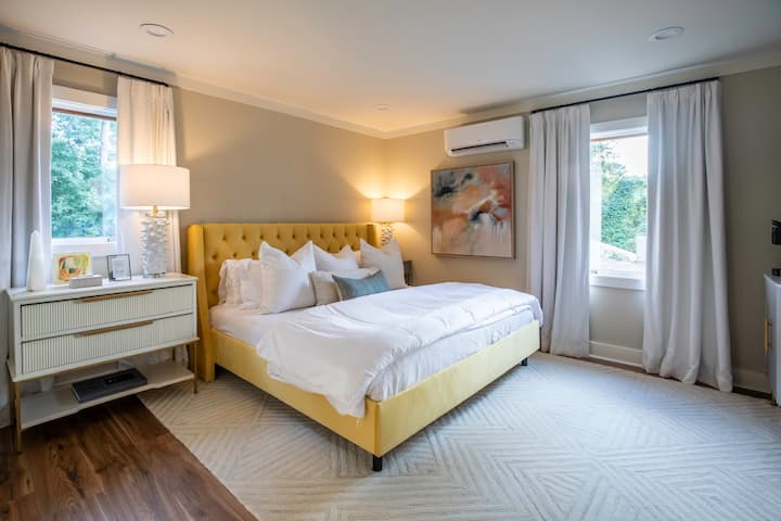 Një dritare e madhe lejon që drita natyrale të mbushë hapësirën, duke nxjerrë në pah krevatin e madhësisë king dhe dekorin përreth tij.