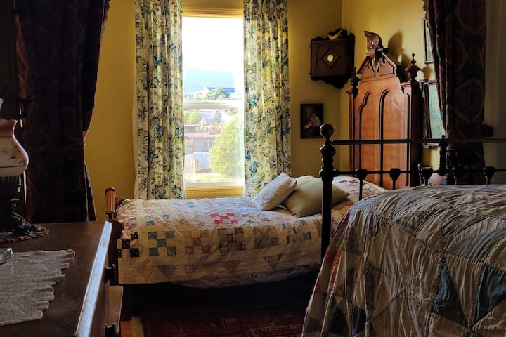 Спалня, предлагаща две удобни единични легла с тежки антични завеси за уединение, които да разделят помещението, ако желаете.