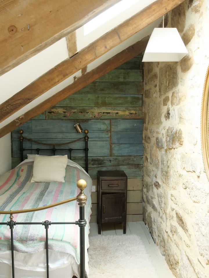 Acogedor dormitorio tipo loft con revestimiento de carácter y vigas expuestas