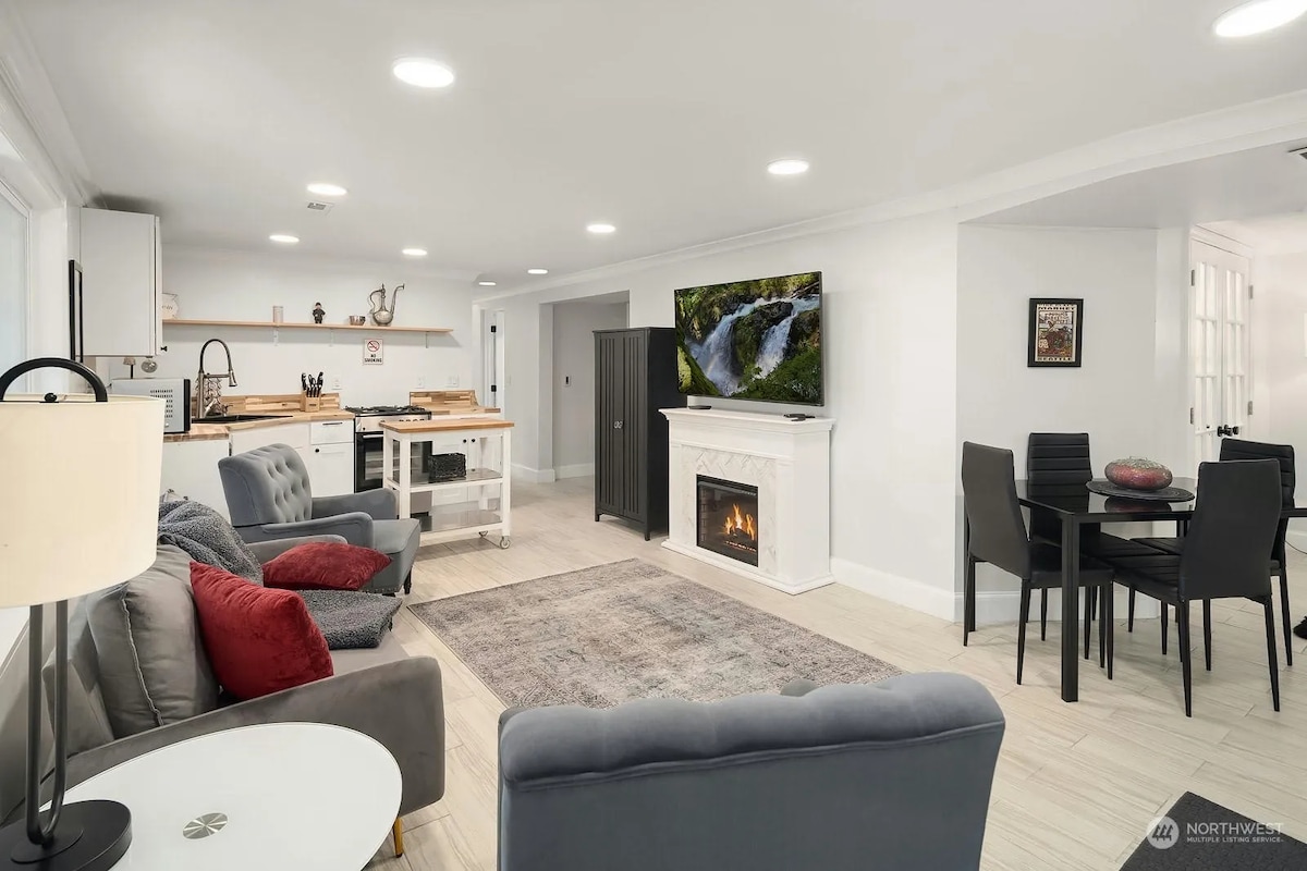 Full kitchen, living area, and dining table visible.

Please note that some furniture has been updated since this photo was taken, such as the removal of the fireplace. This is the view upon entering through the front door.