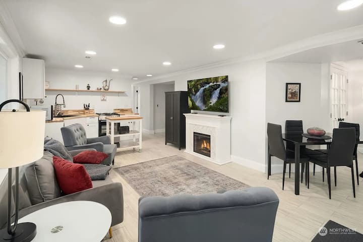 Full kitchen, living area, and dining table visible.

Please note that some furniture has been updated since this photo was taken, such as the removal of the fireplace. This is the view upon entering through the front door.