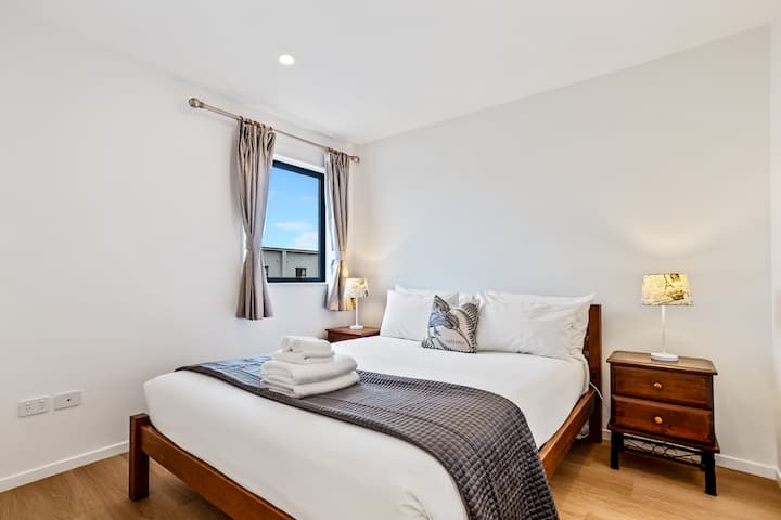 Posteľ Queen vyzerá lákavo s ostrou bielou posteľnou bielizňou a pohodlným prehozom.