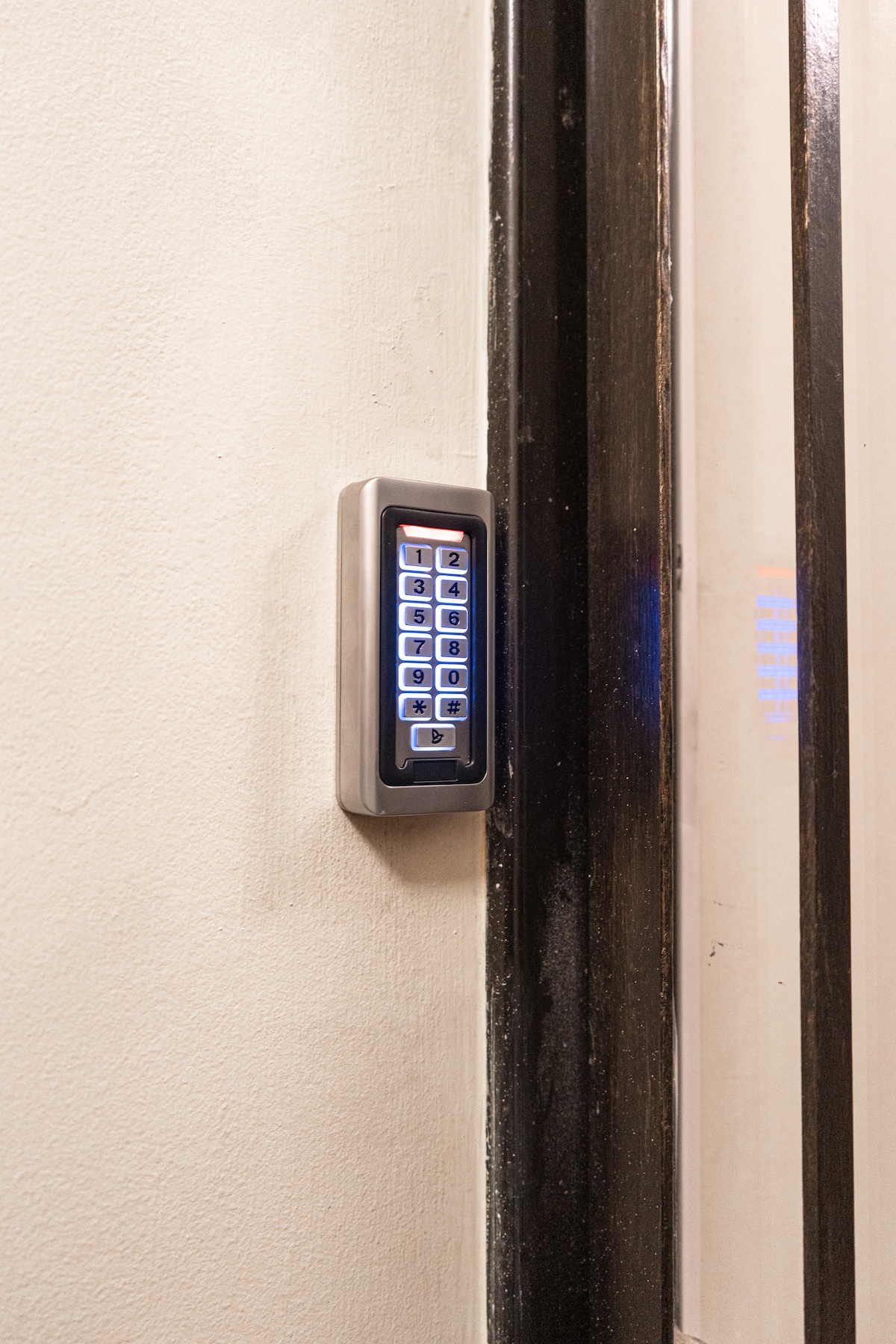 A secure entry system is visible beside a door, featuring a numeric keypad with illuminated buttons. The keypad is mounted on a light-colored wall, providing an accessible means of access to the property.