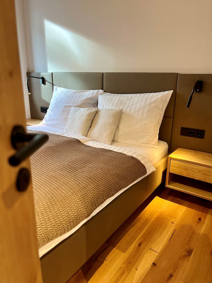 Dormir et travailler : la première chambre dispose d'un lit double (180 cm x 200 cm), d'une armoire et d'un lieu de travail.