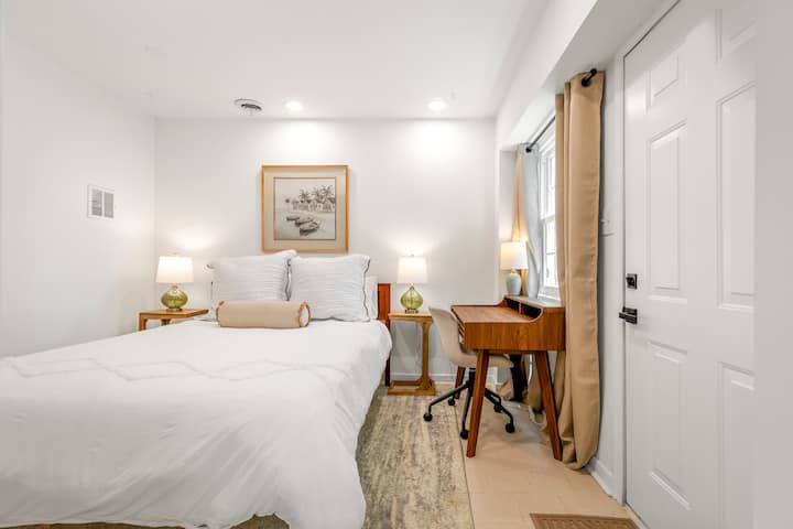 Chambre lumineuse et confortable au niveau inférieur avec literie moelleuse, deux tables de chevet et un petit bureau, idéale pour le repos et le télétravail.