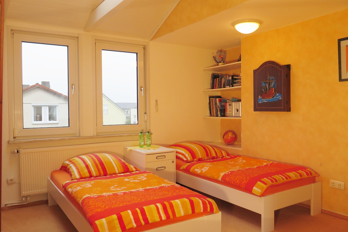 Izba Jan s výhľadom na našu miestnu horu Taunus a záhradu. Dve jednolôžka (90 x 200) a jedna poschodová posteľ (80 x 200 cm) pre tretiu osobu, izba na prvom poschodí. 