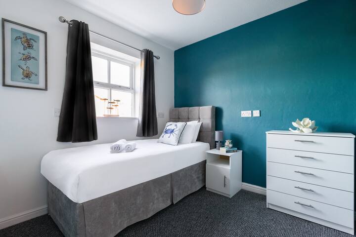 Კომფორტული საძინებელი ორი ერთადგილიანი საწოლით, თითოეული მათგანი შესანახი უჯრით, რომელსაც ემატება კედლის ელეგანტური ხელოვნება და ელეგანტური ფარდები, რაც მყუდრო და მიმზიდველ ატმოსფეროს ქმნის.