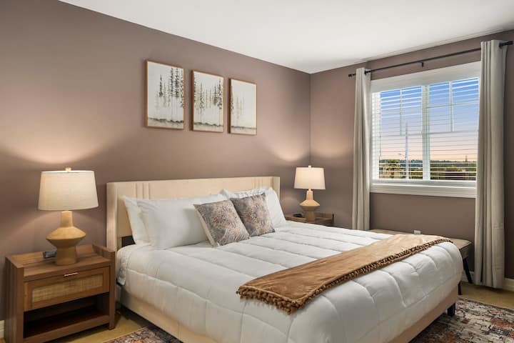 Chumba cha 3 cha kulala cha Mgeni kilicho na dirisha linaloelekea Kusini.  Chumba hiki kina kitanda kizuri cha ukubwa wa King kilicho na meza zilizo na maduka ya umeme yanayofaa na bandari za kuchaji za USB.   Kioo kirefu kiko ukutani.  Madirisha yana mapazia yanayozuia mwanga.