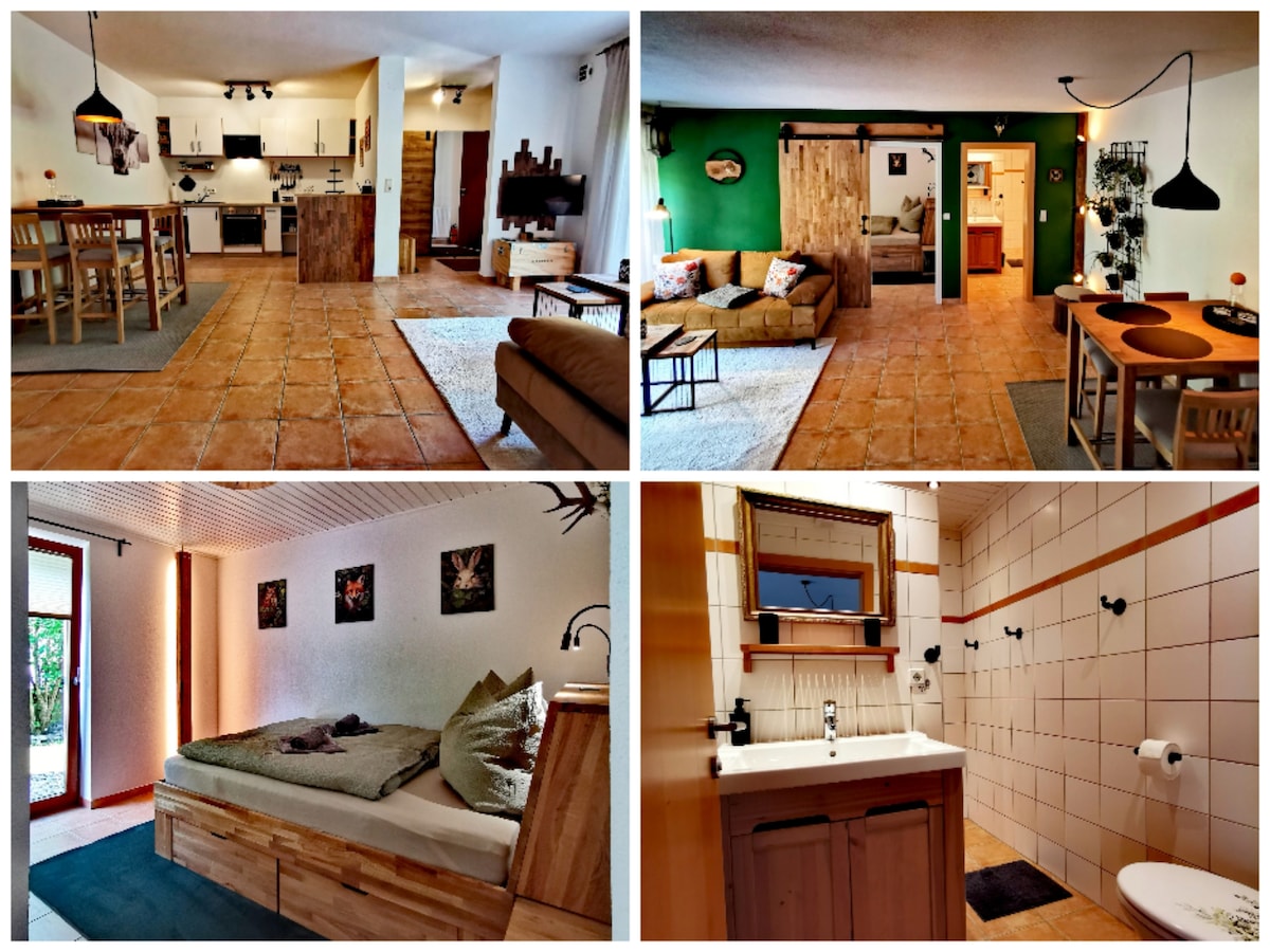 A spacious living area is highlighted by a dining table and open kitchen with modern appliances. A cozy seating area includes a comfortable sofa and coffee table. The sleeping space features a sizable bed with decorative artwork. A bright bathroom includes a sink and shower amenities.