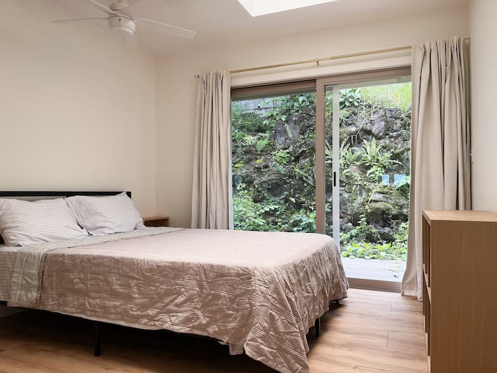 Dormitorio de invitados con cama tamaño queen, puertas correderas de vidrio a la parte trasera de la casa, estante de almacenamiento de cubos y armario pequeño.