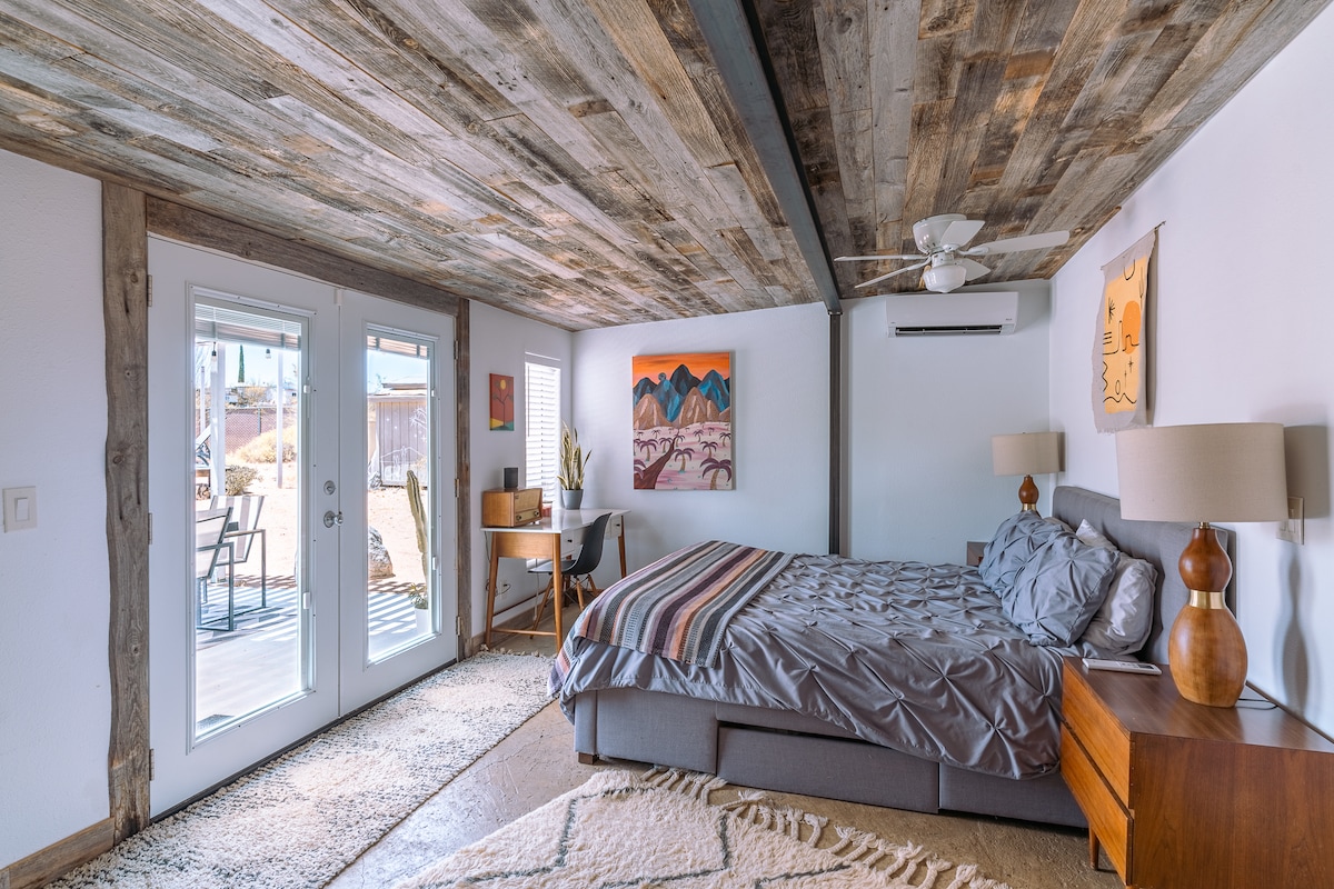Despiértate con la luz natural en un dormitorio acogedor y rústico con acceso directo al patio, perfecto para disfrutar de las tranquilas mañanas del desierto desde tu cama.
