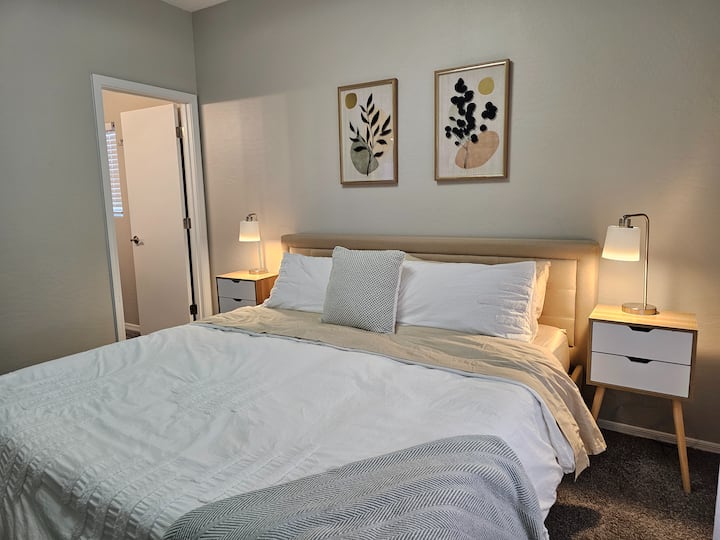 Veľká manželská posteľ, nočné stolíky a lampy. Cez dvere je hlavná kúpeľňa. 