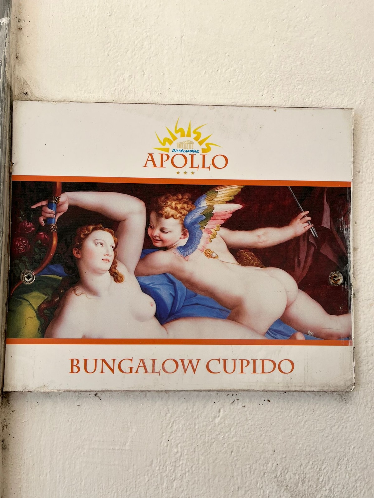 A wall sign identifies the space as 'Bungalow Cupido,' featuring classical artwork depicting figures adorned with vibrant colors. The sign is framed with a logo and the name 'Apollo,' contributing to the artistic ambiance of the area.