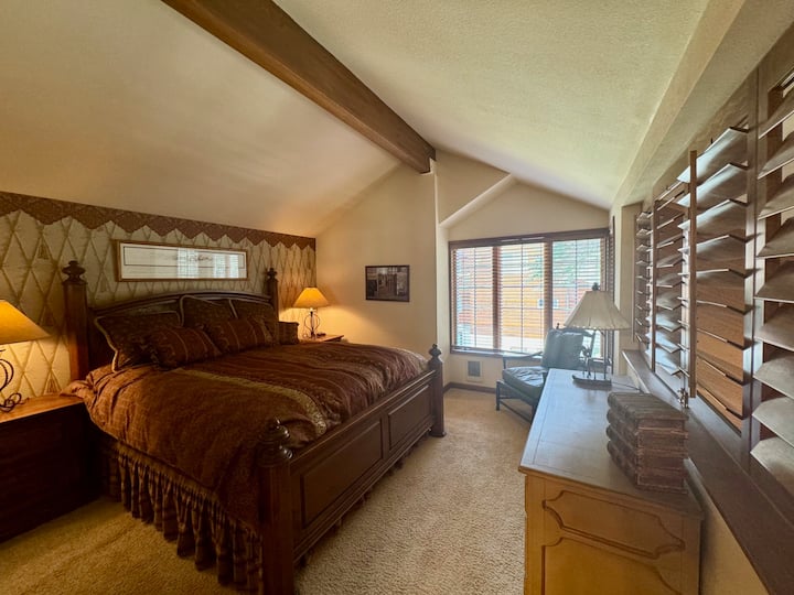 חדר שינה בלופט בקומה השנייה של הבית. חצי קיר עם תריסים שנפתחים לסלון למטה.