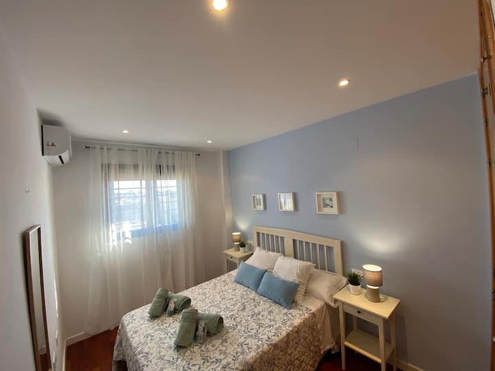 Spavaća soba s bračnim krevetom, ormarom i klima-uređajem.