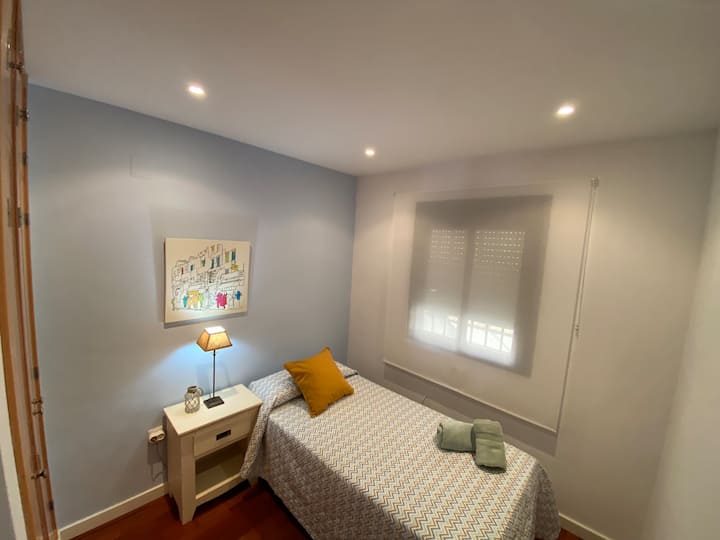 Soba s dva odvojena kreveta, ormarom i prijenosnim ventilatorom. 