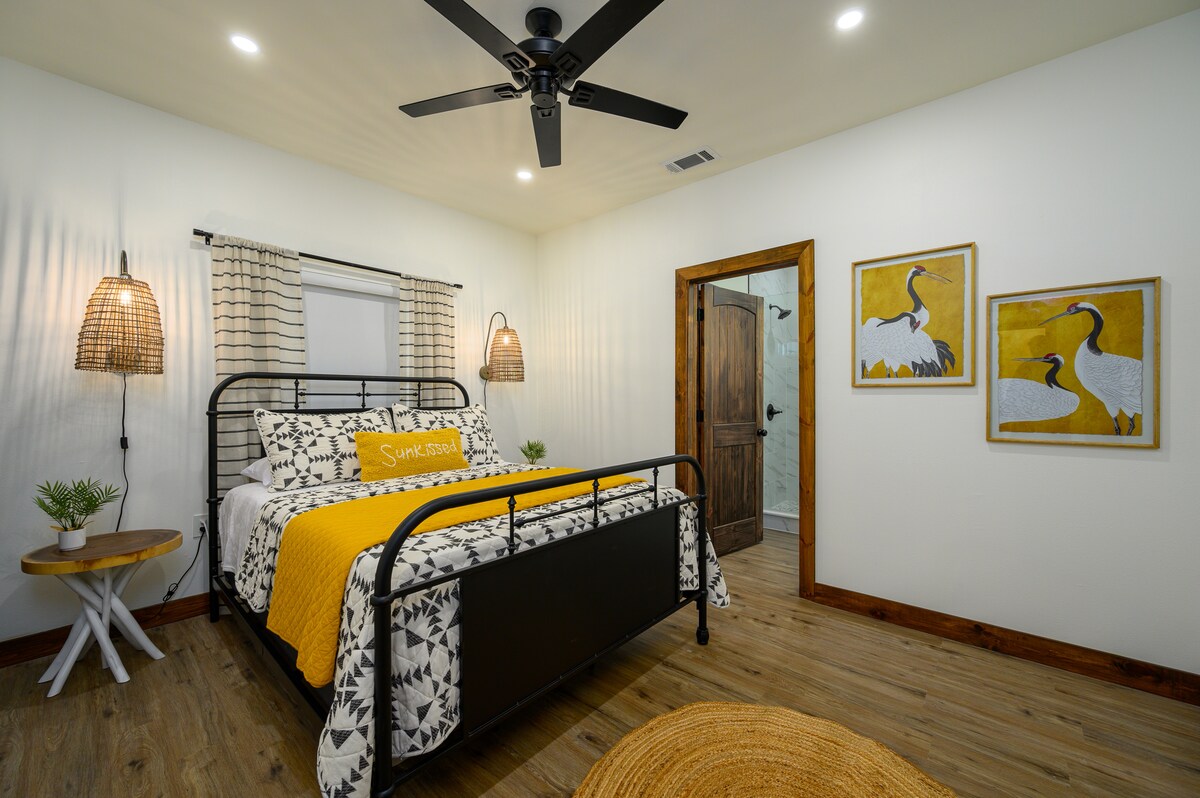 De gele kamer heeft een queensize bed, luxe beddengoed en een eigen badkamer met een staande douche. 