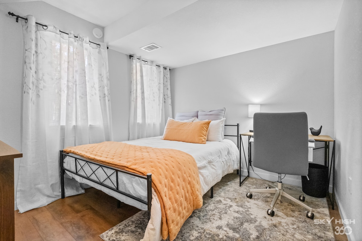Dormitorio tamaño queen en la planta baja con espacio de trabajo y TV.  