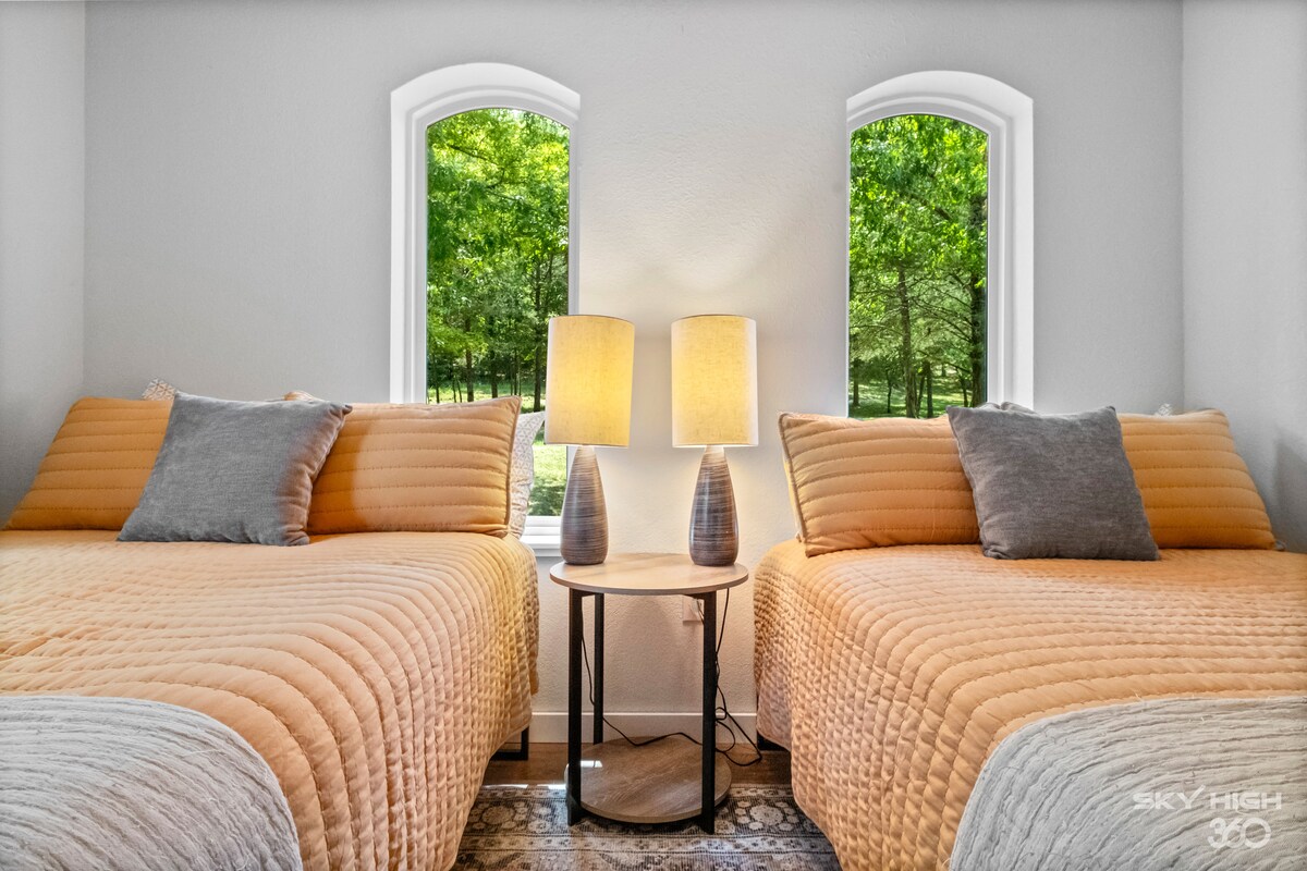 Dormitorio con dos camas de matrimonio y hermosas vistas al aire libre, las copas de los árboles y el lago.  