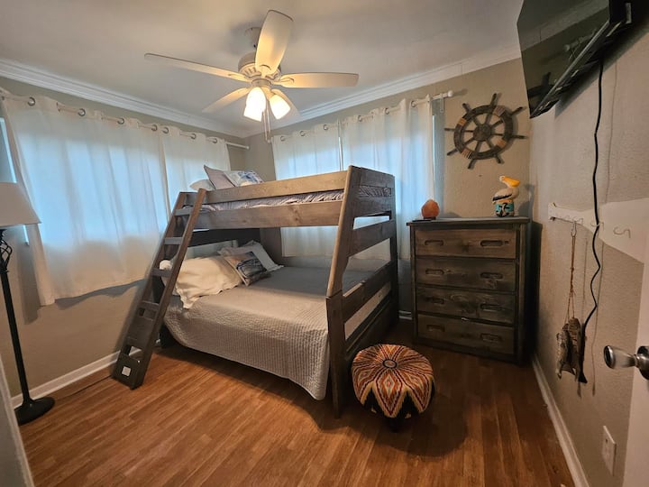 Двуетажната стая. Разполага с ново двуетажно легло с двойно легло отдолу и горна част на единично легло с нови матраци. Хубав скрин, достатъчно пространство в килера и младежки декор правят тази стая наистина забавна за всички!