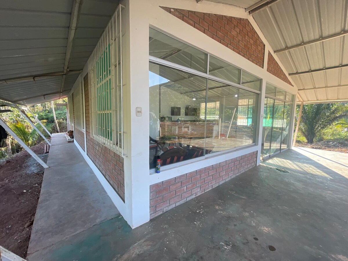 A spacious exterior view of the house features large windows that provide ample natural light. The structure is framed by greenery, showcasing a blend of brick and siding. An inviting pathway leads toward the entrance, emphasizing the connection with the natural surroundings.