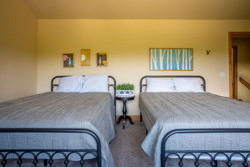 غرفة نوم في الطابق العلوي مع 2 سرير. تحتوي غرفة النوم هذه أيضًا على تلفزيون.