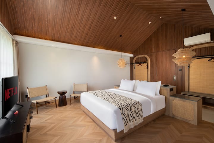 Lit King Size de marque King Koil, coin salon, télévision connectée 42 pouces avec Netflix et autres services de streaming, climatiseur et placard puissants.