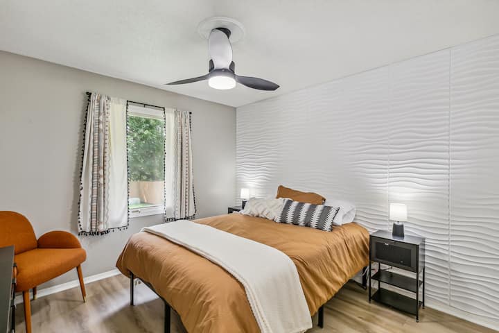 Spálňa s manželskou posteľou - 2 dospelí. Táto štýlová biela a oranžová izba má krásnu stenu s prízvukom vĺn. Každý nočný stolík má nabíjacie stanice. Sadnite si a navštívte pohodlnú stoličku Modern z polovice storočia, zatiaľ čo si vychutnáte chladný vánok, stropný ventilátor. 