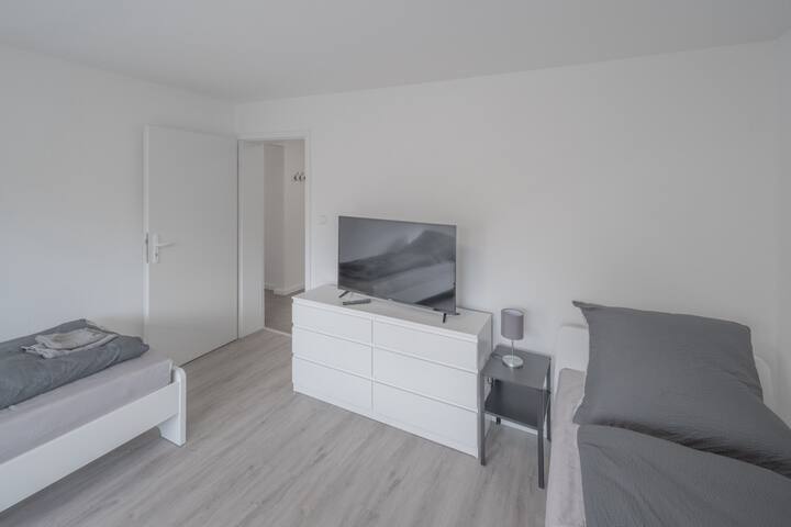 Spálňa s tromi lôžkami, zásuvkami a televízorom