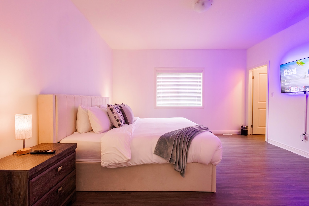 Chumba kipana cha kulala chenye kitanda cha kifahari cha king, mwanga laini na televisheni janja iliyowekwa — kinatoa mapumziko ya starehe na mwanga wa kisasa wa kupumzika.