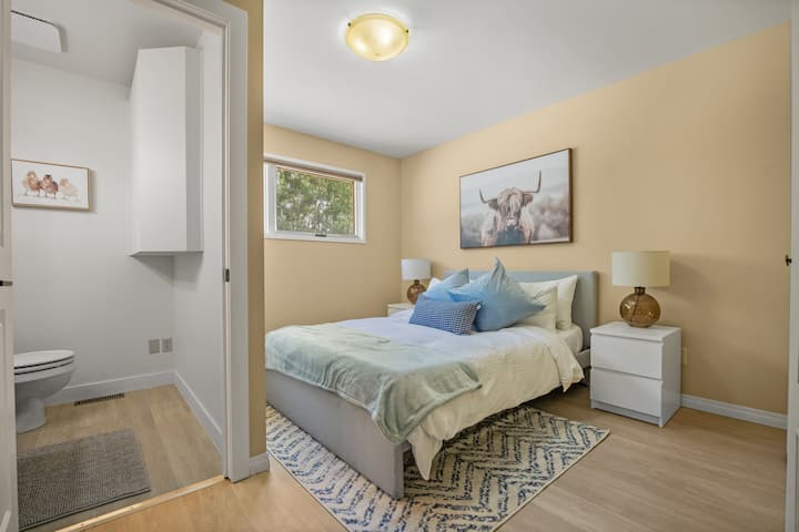 חדר שינה ראשי בקומה הראשית עם מיטת קווין סייז וחדר שירותים צמוד פרטי.