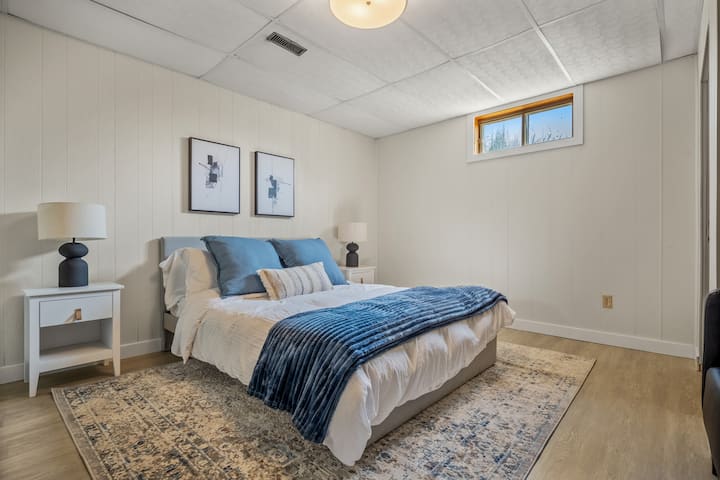 חדר שינה שלישי למטה עם מיטת קווין סייז, ארון וטלוויזיה חכמה.