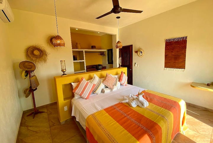 חדר שינה פרטי בקומה השנייה עם מיטת קינג סייז, אמבטיה מלאה ומרפסת עם נוף לים. 