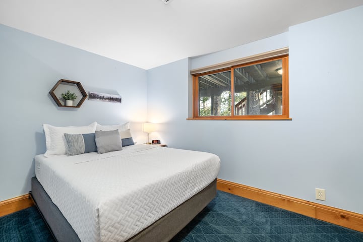 Kitanda chenye starehe kwenye ghorofa ya chini, kilicho na meza ya pembeni, taa na mashuka ya kifahari kwa ajili ya kulala vizuri usiku.
