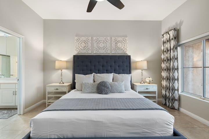 Dormitorio principal con cama tamaño king, TV inteligente montada en la pared con servicios de cable y baño privado adjunto con amplio vestidor.