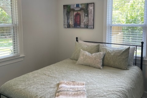 Segundo dormitorio con colchón Sealy tamaño queen nuevo e imágenes de sitios locales en Charleston.  Dos mesitas de noche, un armario y un portaequipajes completan esta habitación.