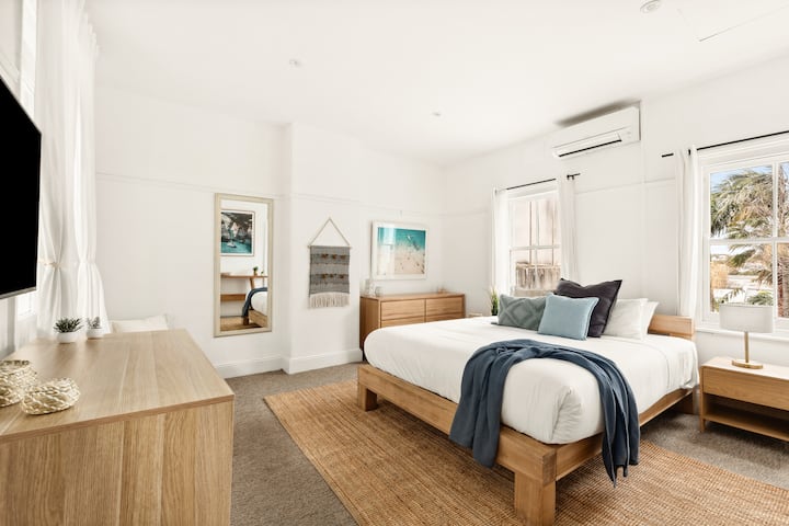 Relax in the huge main bedroom upstairs, featuring a comfortable king-sized bed, stylish decor, and ample natural light. Perfect for unwinding after a day exploring the city, this serene retreat ensures a restful night's sleep in a beautiful setting.