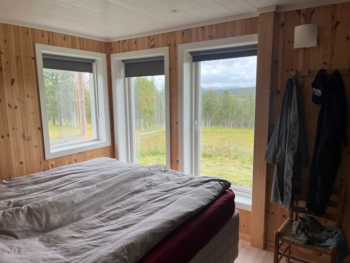 El dormitorio 1 tiene una cama doble (B = 180 cm). Ventanas orientadas al este y al norte.  Si es la época del año, puedes ver hierba de alce en el borde del bosque.