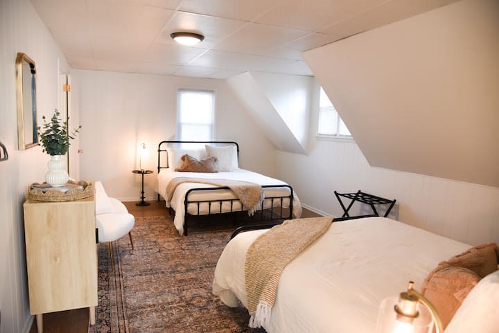 Chambre spacieuse au deuxième niveau avec deux lits queen + lampes de table de chevet avec ports de recharge.