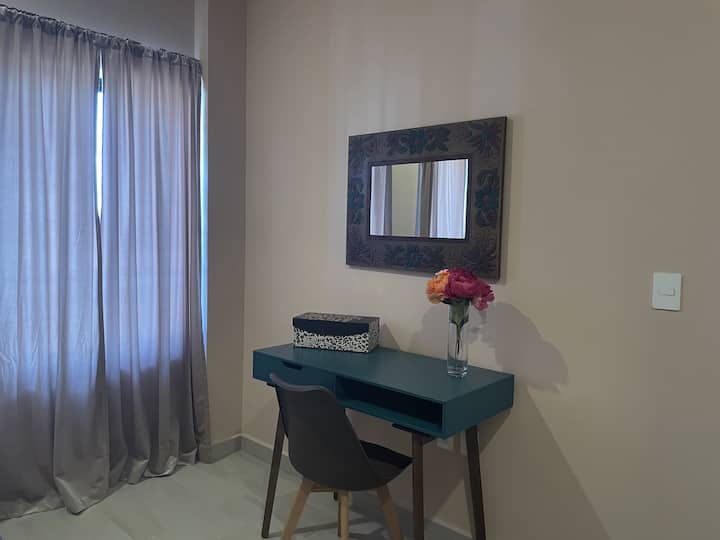 Este acogedor espacio de trabajo en el dormitorio tamaño king incluye un elegante escritorio de color verde oscuro, una cómoda silla y vibrantes obras de arte. Bañado con luz natural desde una ventana cercana, ofrece un lugar sereno e inspirador para el trabajo o la creatividad.