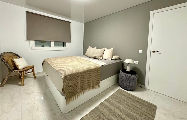 Спална соба 1 со јужна атмосфера и двоен кревет со многу висок над стандарден удобен  душек од 200 см. Ноќни масички, светилки и штекери покрај креветот. Просторен мебел и закачалка.