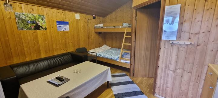 Дървена колиба № 2 - родителска стая с диван, маса и двуетажни легла.