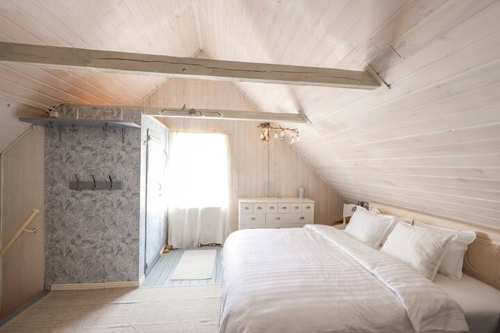 Ova spavaća soba ima i WC u brvnari (mala soba s lijeve strane s plavo-bijelim tapetama).